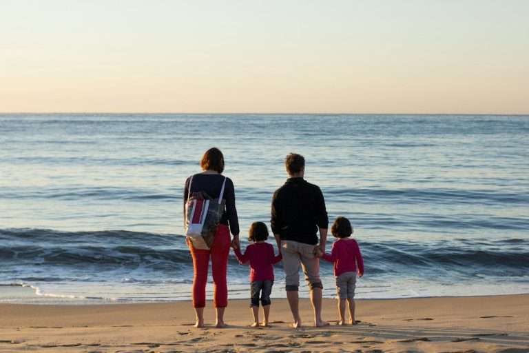 Family of four standing together at the seashore on holiday